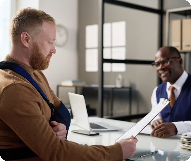 A man reading a legal document in the foreground with a black man smiling in the background