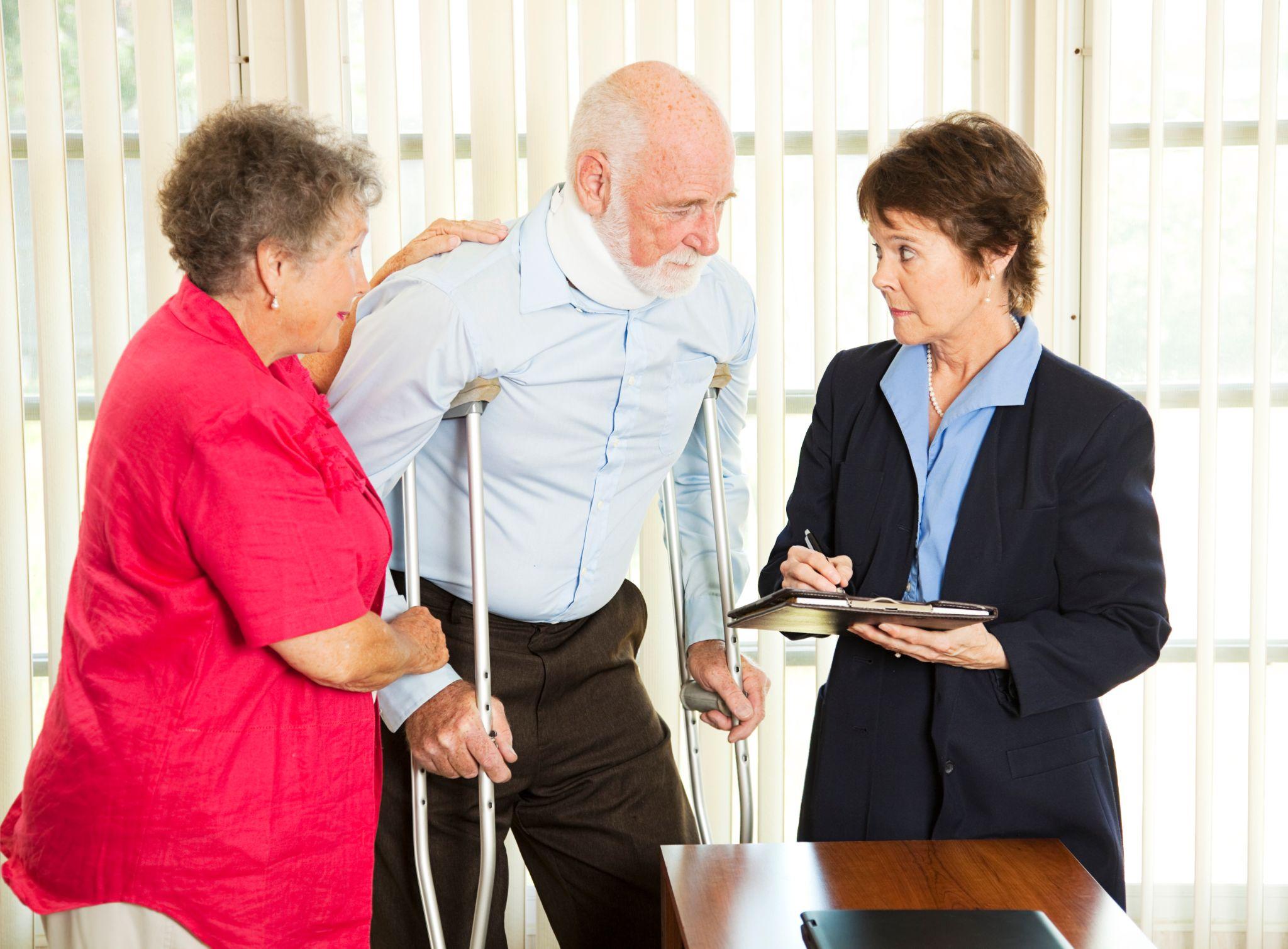 Elderly man on crutches with neck brace talking to lawyer.